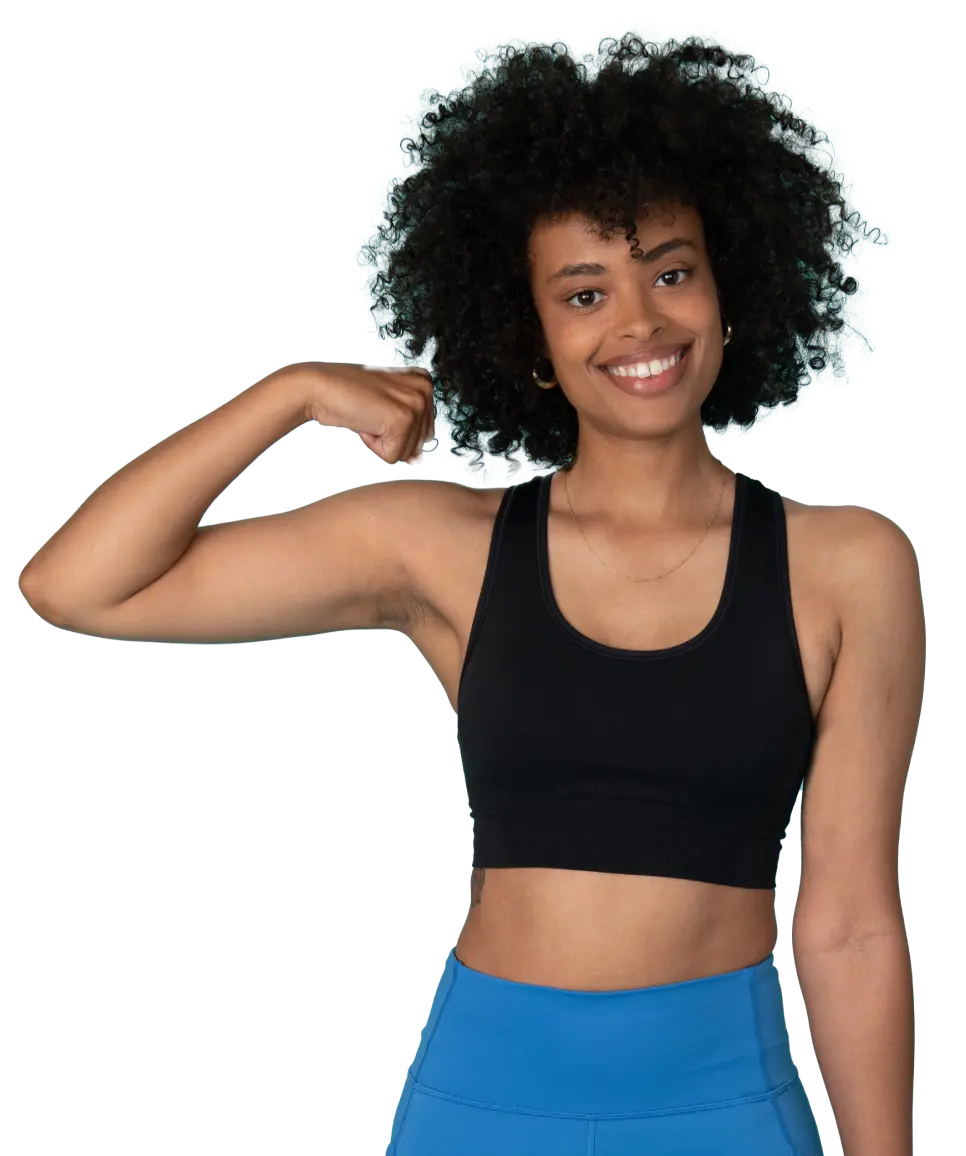 African American athletic woman with curly hair in sportswear smiles at the camera while flexing her right arm