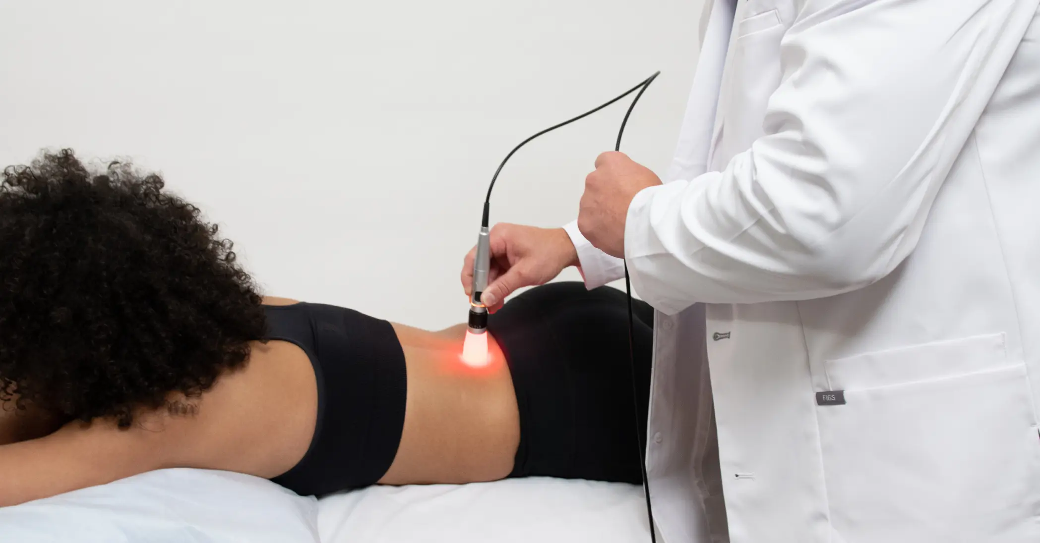 Photobiomodulation; doctor providing laser therapy treatment to a young woman's back