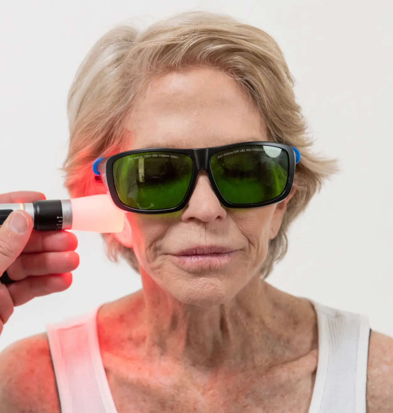 Dental; laser therapy treatment to elder woman's jaw; patient is wearing protective goggles